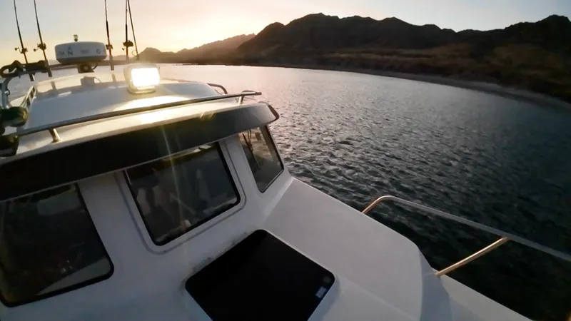Slide: The Image of 2009 C-Dory TOMCAT 255 boat cruising on a serene lake at sunset. - 79