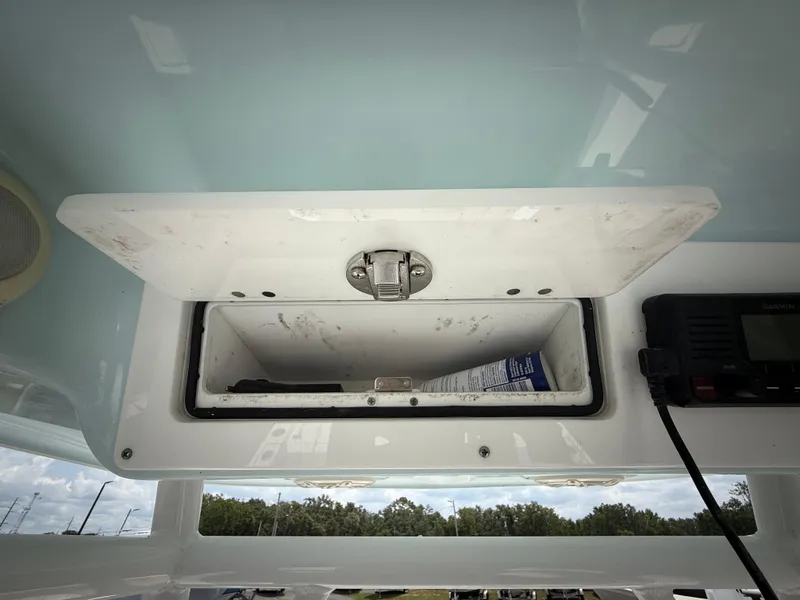 Slide: The Image of 2020 Sportsman Masters 247 Bay Boat storage compartment with latch and radio equipment. - 28