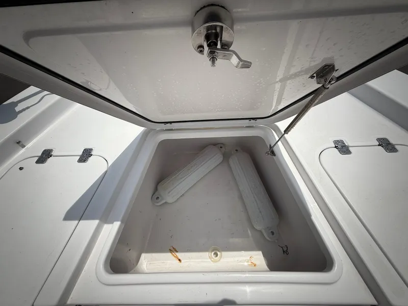 Slide: The Image of 2020 Sportsman Masters 247 Bay Boat storage compartment with open lid and boat fenders inside. - 46
