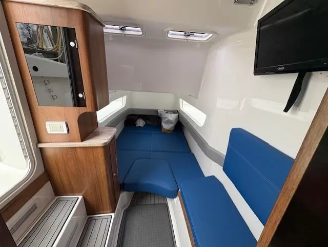 Slide: The Image of 2018 Invincible 42 CC cabin interior with blue seating, wooden cabinetry, and mounted TV. - 14