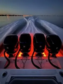 Slide: The Image of 2018 Invincible 42 CC boat with four illuminated engines cruising at sunset. - 21