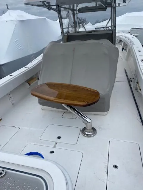 Slide: The Image of 2018 Invincible 42 CC boat interior with wooden table and covered seating. - 6