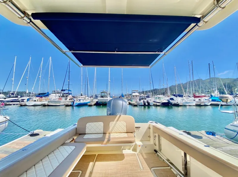 Slide: The Image of 2020 Chris-Craft Calypso 26 boat docked in a marina with sailboats and clear blue sky. - 17