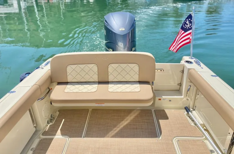 Slide: The Image of 2020 Chris-Craft Calypso 26 boat with cushioned seating and American flag on calm water. - 18