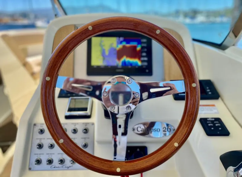Slide: The Image of 2020 Chris-Craft Calypso 26 helm with wooden steering wheel and navigation display. - 24