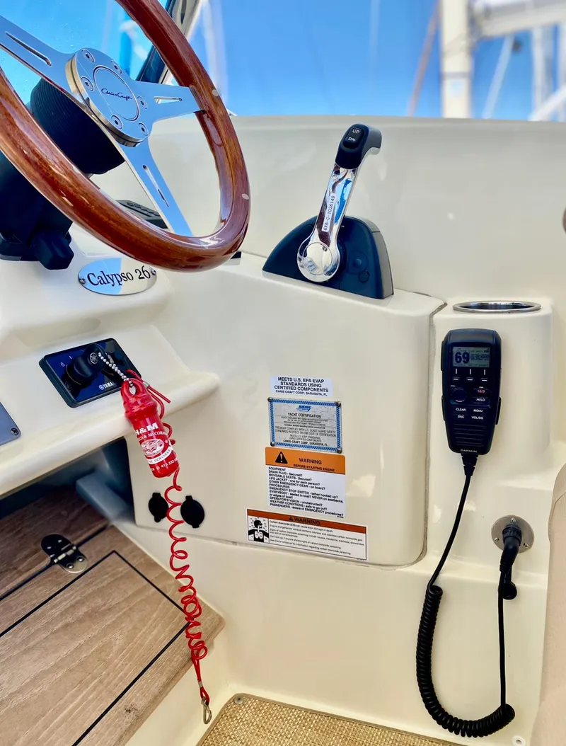 Slide: The Image of 2020 Chris-Craft Calypso 26 helm with steering wheel, throttle, and marine radio. - 26