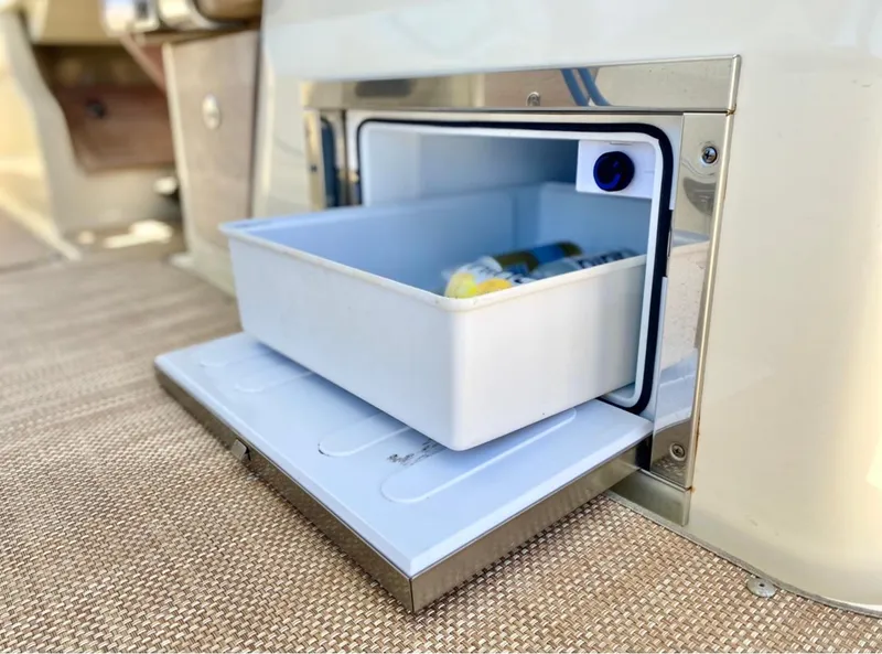 Slide: The Image of 2020 Chris-Craft Calypso 26 boat cooler compartment with open storage drawer. - 30