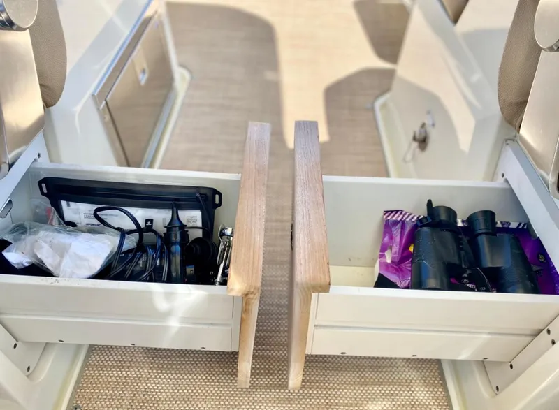 Slide: The Image of 2020 Chris-Craft Calypso 26 interior storage drawers with binoculars and accessories. - 31