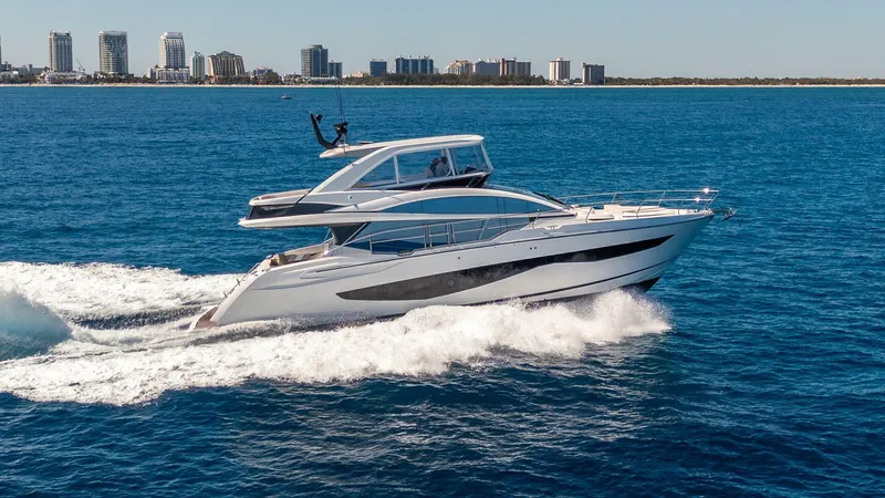 Slide: The Image of 2023 Pearl 62 yacht cruising on blue ocean with city skyline in background. - 2