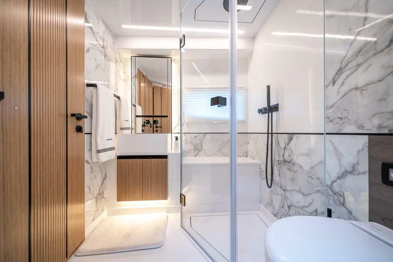 Slide: The Image of Luxurious modern bathroom with marble walls, glass shower, and wooden accents in a 2023 Pearl 62. - 36