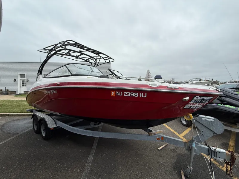 Slide: The Image of 2016 Yamaha Boats 242 Limited S E-Series on trailer, red exterior, parked outdoors. - 19