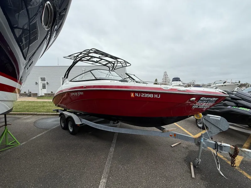 Slide: The Image of 2016 Yamaha Boats 242 Limited S E-Series on trailer, red exterior, parked outdoors. - 20