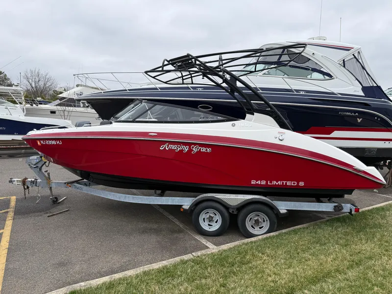 Slide: The Image of 2016 Yamaha 242 Limited S E-Series boat in red on a trailer, parked in a marina. - 23