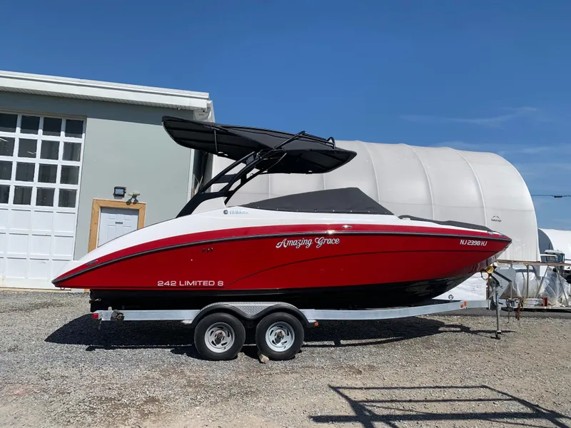 Slide: The Image of 2016 Yamaha Boats 242 Limited S E-Series on trailer, red and white, parked outdoors. - 7