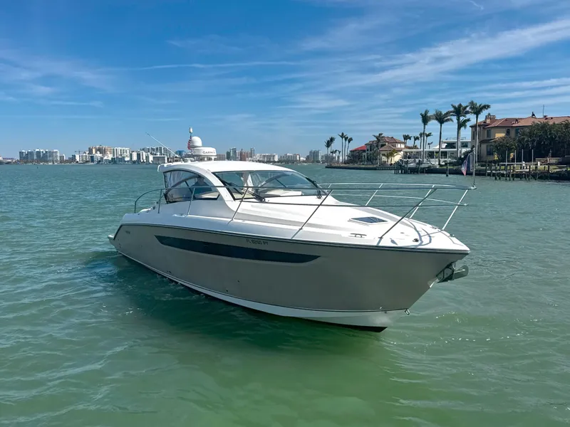 Slide: The Image of 2015 Pursuit SC 365i Sport Coupe on calm water, with cityscape and palm trees in background. - 1