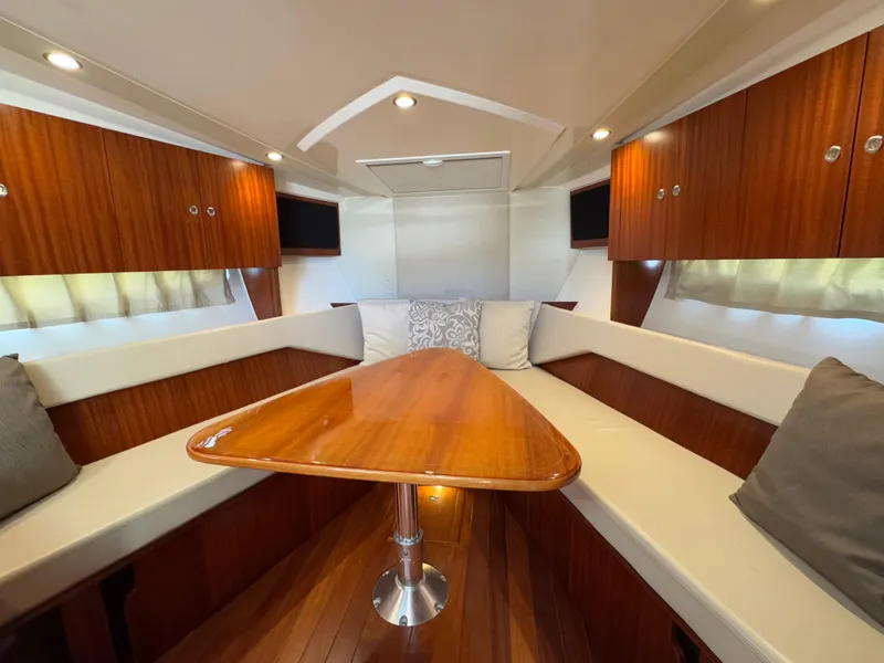 Slide: The Image of 2015 Pursuit SC 365i Sport Coupe interior with wooden table and cushioned seating. - 10
