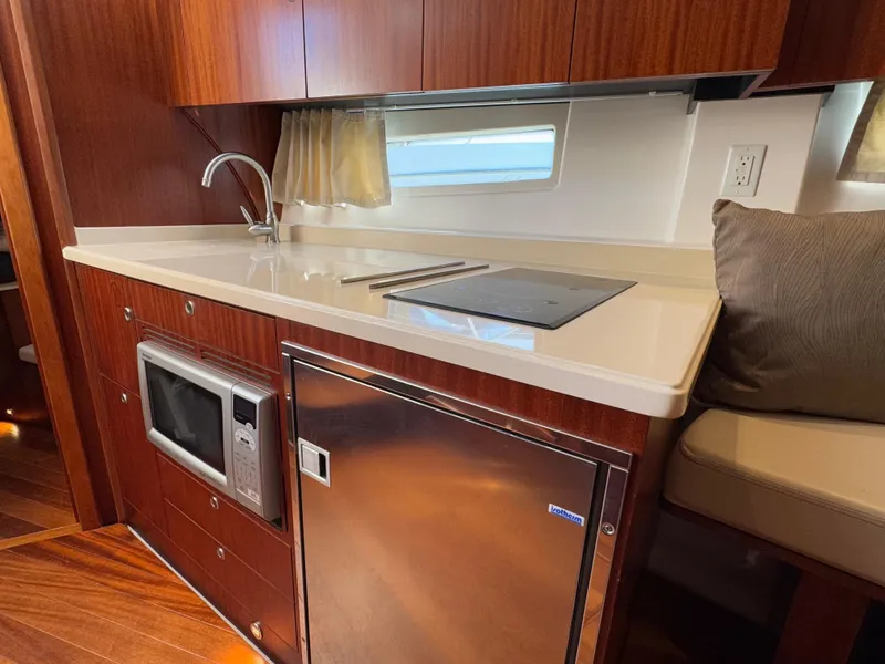 Slide: The Image of 2015 Pursuit SC 365i Sport Coupe kitchen with microwave, fridge, and sleek countertop. - 18