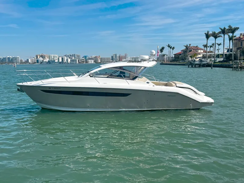 Slide: The Image of 2015 Pursuit SC 365i Sport Coupe on calm water, cityscape background. - 2