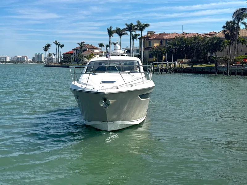 Slide: The Image of 2015 Pursuit SC 365i Sport Coupe yacht on calm water near luxury waterfront homes. - 4