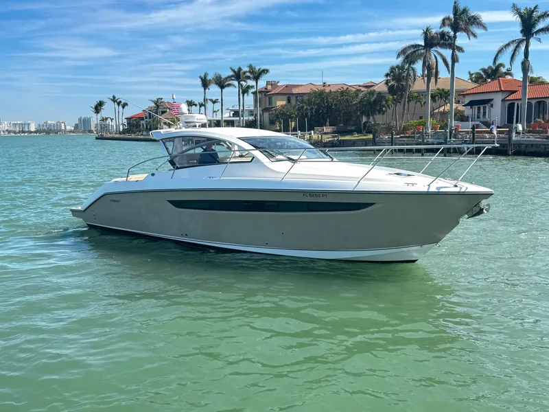 Slide: The Image of 2015 Pursuit SC 365i Sport Coupe on tranquil water near luxury waterfront homes. - 5