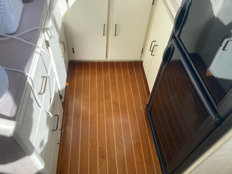 Slide: The Image of 1984 Mainship 40 DC Sundeck kitchen with wood flooring and white cabinetry. - 16