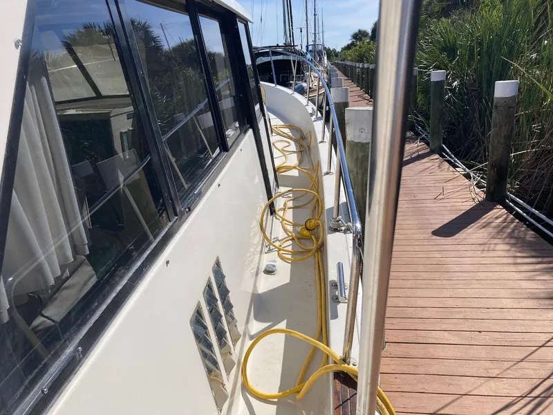 Slide: The Image of 1984 Mainship 40 DC Sundeck docked, showing side view with yellow cables. - 6