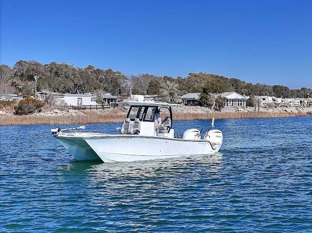 Slide: The Image of 2024 Freeman 28 boat on calm water with scenic shoreline background. - 2