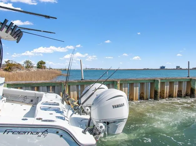 Slide: The Image of 2024 Freeman 28 boat with Yamaha engines docked by a scenic waterfront. - 25