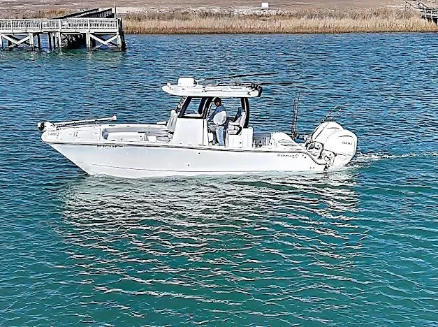 Slide: The Image of 2024 Freeman 28 boat cruising on clear blue water near a wooden dock. - 4