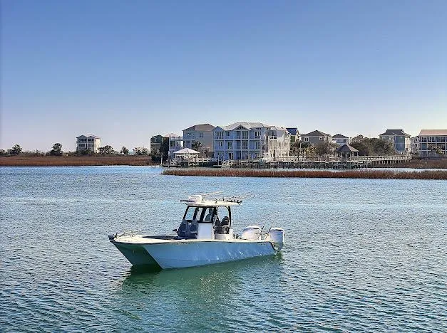 Slide: The Image of 2024 Freeman 28 boat on calm water near coastal homes under clear blue sky. - 8