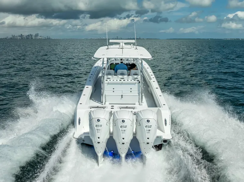 Slide: The Image of 2025 Contender 44 ST boat cruising on open water, rear view with powerful engines. - 12