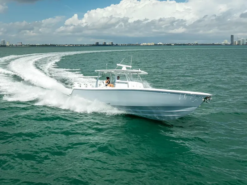 Slide: The Image of 2025 Contender 44 ST boat cruising on open water with city skyline in background. - 14