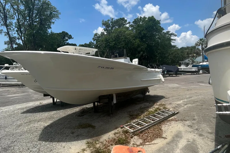 Slide: The Image of 2013 ENVI 25 Offshore Center Console boat on dry dock, surrounded by trees and clear sky. - 1