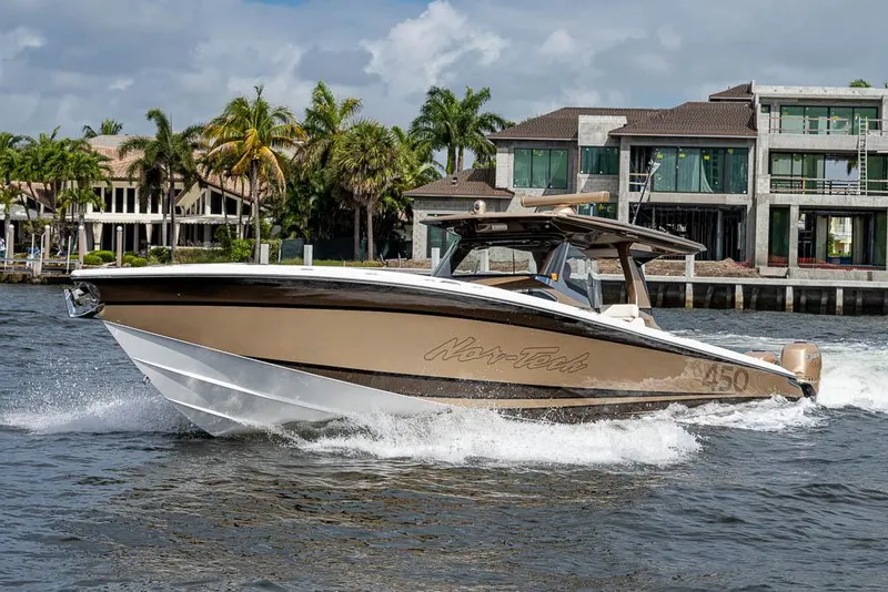 Slide: The Image of 2019 Nor-Tech 450 Sport Center Console boat cruising on water near luxury waterfront homes. - 34