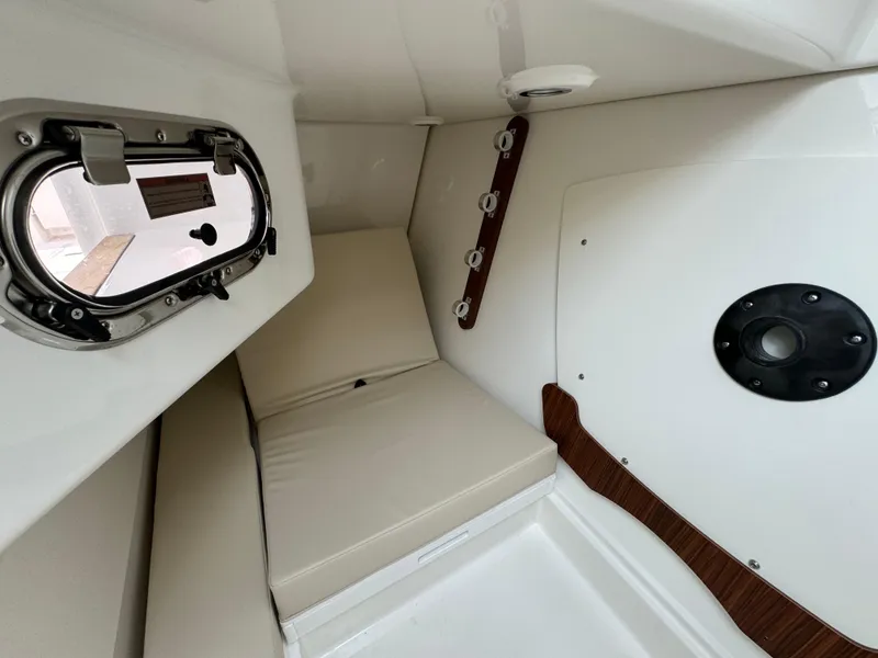 Slide: The Image of 2025 Pursuit DC 326 cabin interior with cushioned seating and porthole window. - 24