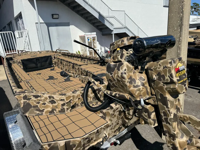 Slide: The Image of 2025 Excel 1860 F4 Shallow Water boat with camouflage design, parked outdoors. - 24