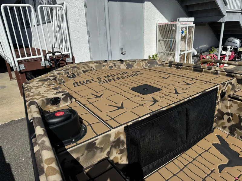 Slide: The Image of 2025 Excel 1860 F4 Shallow Water boat with camouflage design, docked near stairs. - 28