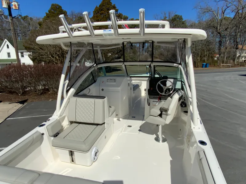 Slide: The Image of 2024 Pursuit DC 246 Dual Console boat with seating and steering wheel, parked outdoors. - 11