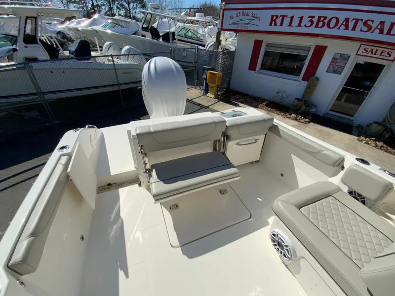 Slide: The Image of 2024 Pursuit DC 246 Dual Console boat interior at dealership, featuring seating and storage. - 17