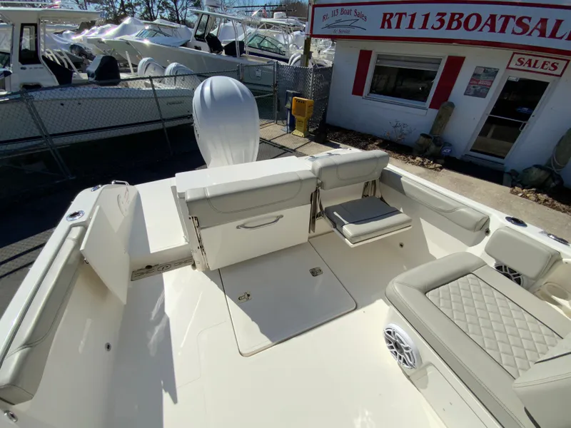 Slide: The Image of 2024 Pursuit DC 246 Dual Console boat interior at dealership, featuring seating and storage. - 18