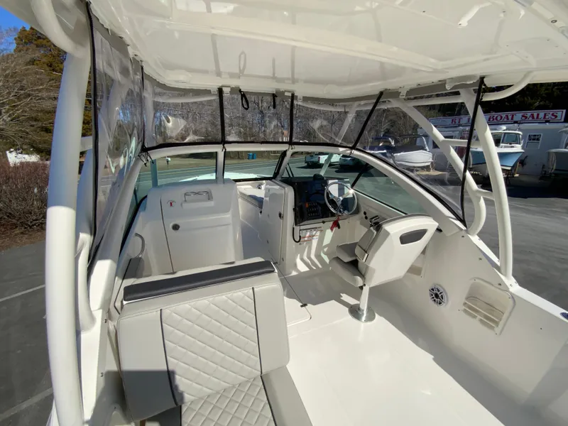 Slide: The Image of 2024 Pursuit DC 246 Dual Console boat interior with seating and helm, showcasing modern design. - 19