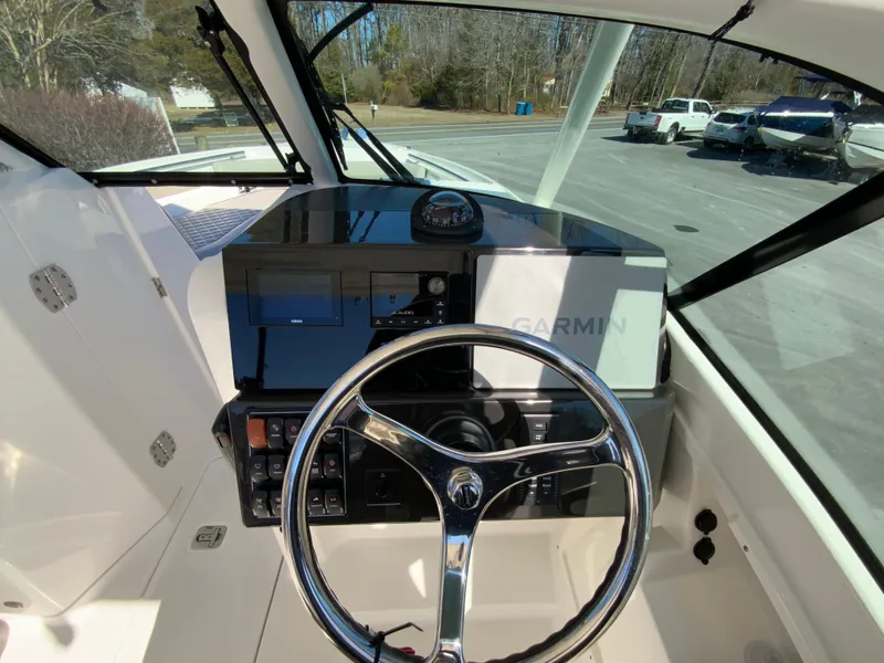 Slide: The Image of 2024 Pursuit DC 246 Dual Console boat dashboard with steering wheel and Garmin navigation system. - 22