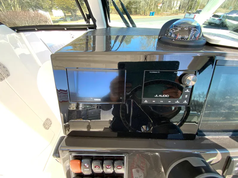 Slide: The Image of 2024 Pursuit DC 246 Dual Console dashboard with JL Audio system and compass. - 24