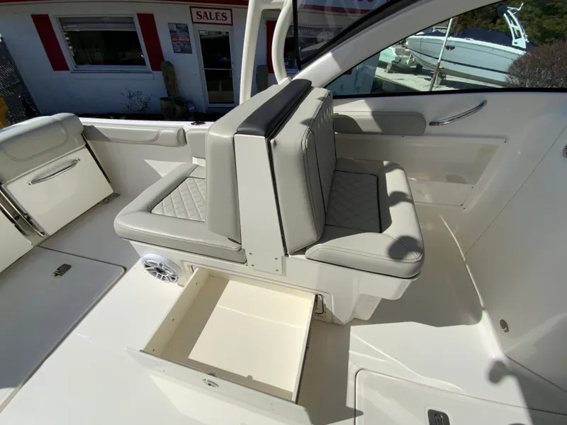 Slide: The Image of 2024 Pursuit DC 246 Dual Console boat interior with cushioned seating and storage compartment. - 28