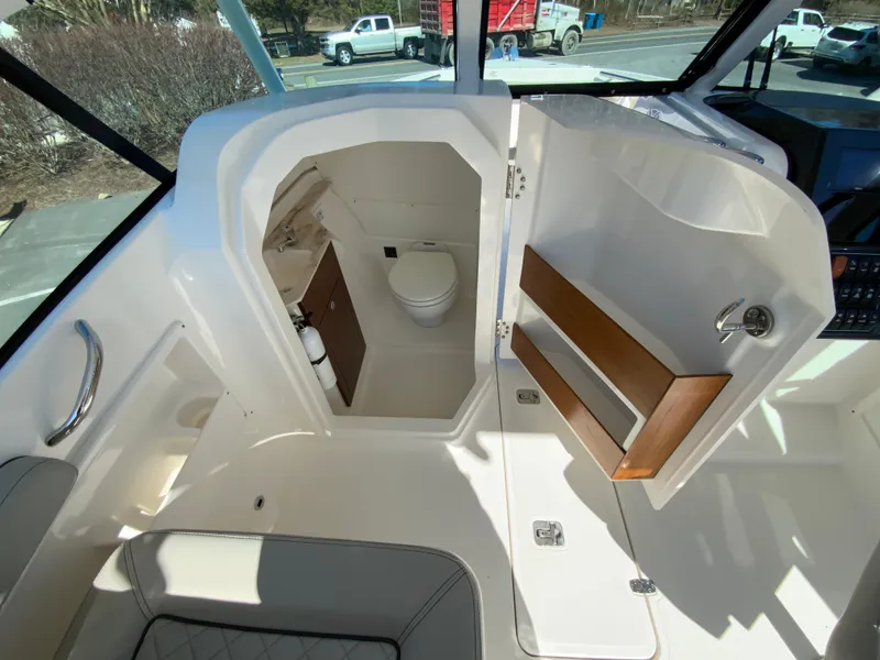 Slide: The Image of 2024 Pursuit DC 246 Dual Console boat interior with open cabin door and visible toilet. - 32