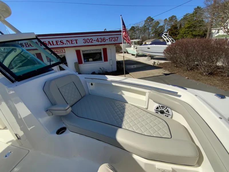 Slide: The Image of 2024 Pursuit DC 246 Dual Console boat with beige seating, displayed at a dealership. - 44