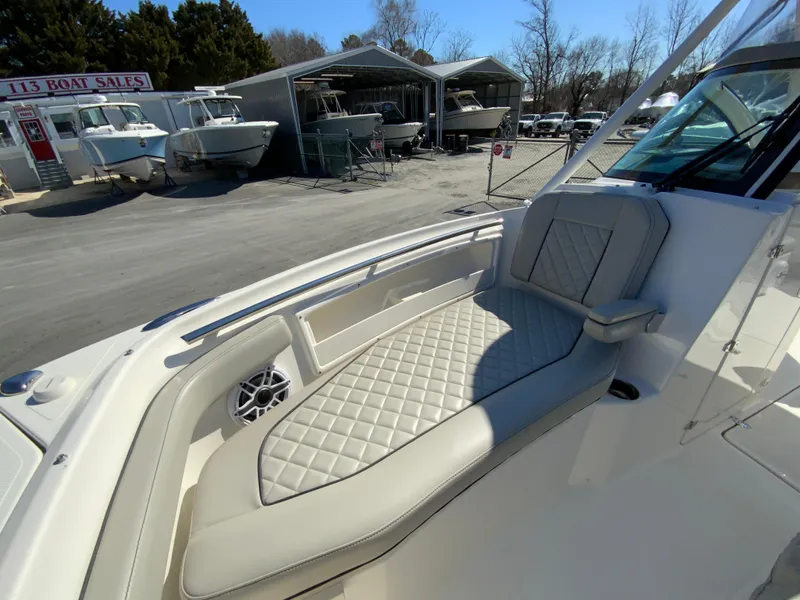 Slide: The Image of 2024 Pursuit DC 246 Dual Console boat with cushioned seating and speaker, displayed at a sales lot. - 45
