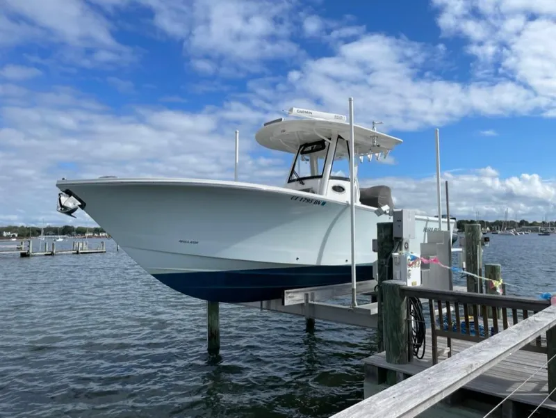 Slide: The Image of 2021 Regulator 28 boat docked on a lift under a partly cloudy sky. - 0