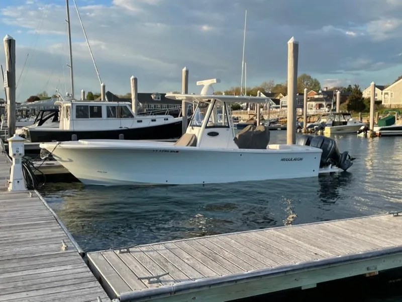 Slide: The Image of 2021 Regulator 28 boat docked at marina under cloudy sky. - 2