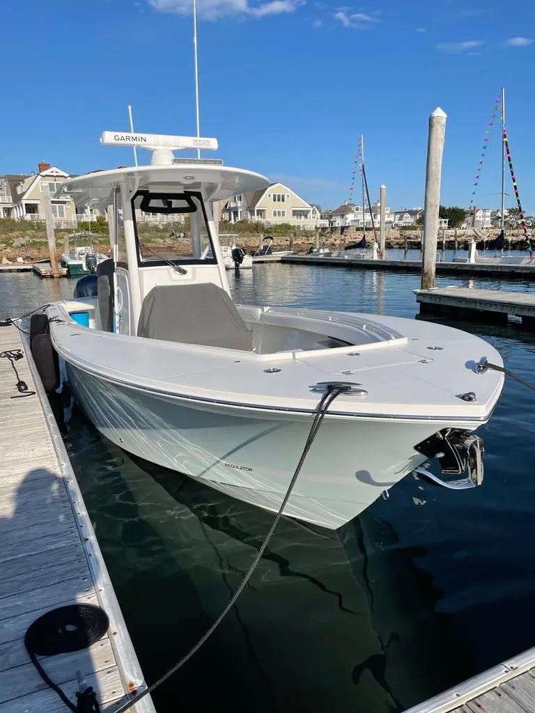 Slide: The Image of 2021 Regulator 28 boat docked in a marina, clear sky, waterfront homes in background. - 4